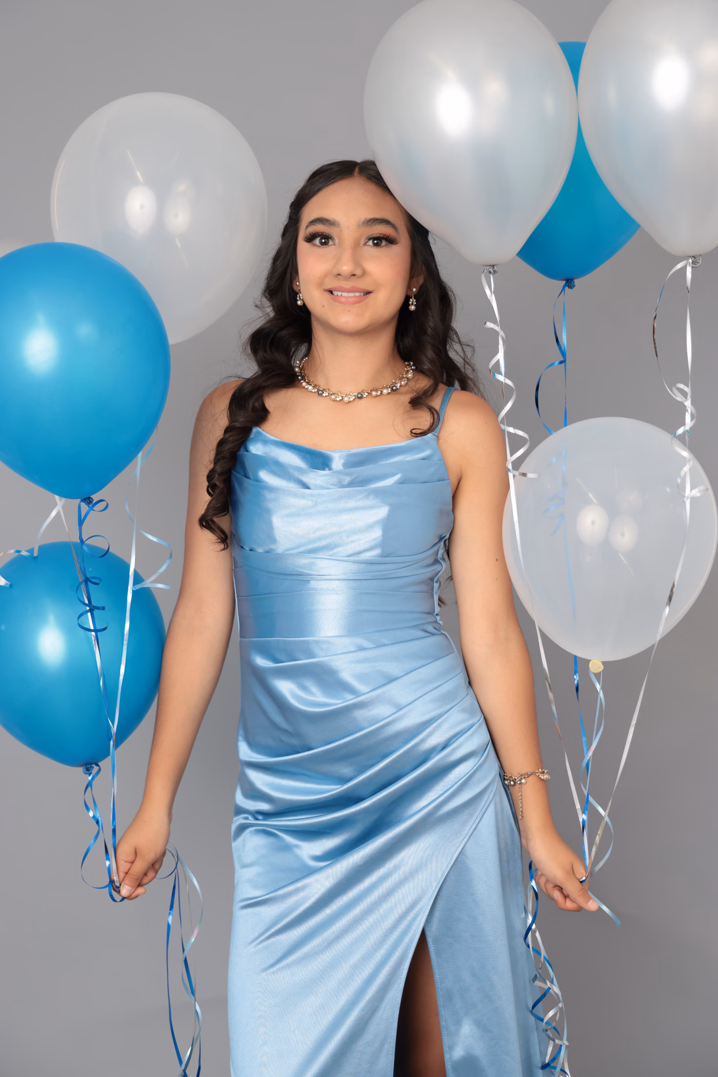 Retrato de quinceañera rodeada de globos azules y plateados